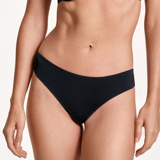 Person wearing black bikini bottoms on a plain background