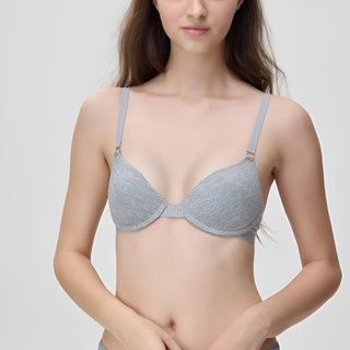 Woman wearing a gray bra against a plain background