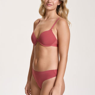 Woman wearing a red bra and panties set on a white background