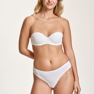 Woman wearing a white strapless bikini against a plain background