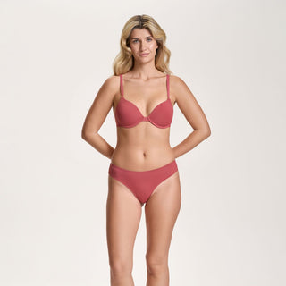 Woman wearing a red bra and panties set on a beige background
