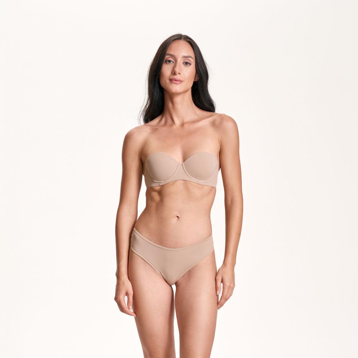 Woman wearing a beige strapless bikini on a white background
