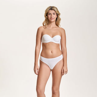Woman wearing a white strapless bikini on a light beige background