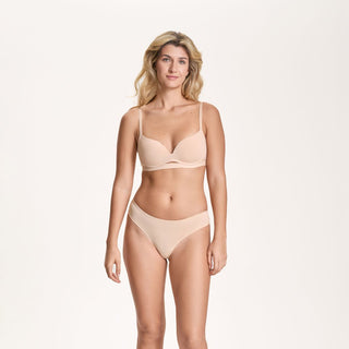 Woman wearing a beige bra and panties set on a white background