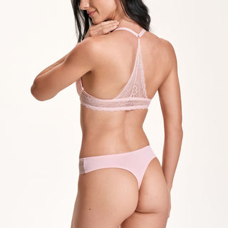 Woman wearing a pink lace lingerie set on a white background
