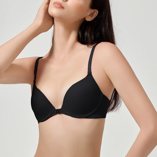 Woman wearing a black bra against a plain background