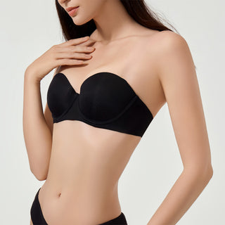 Woman wearing a black strapless bra against a plain background