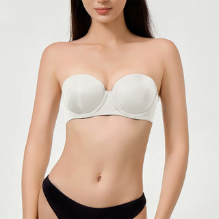 Woman wearing a white strapless bra against a plain background