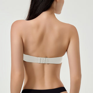 Woman wearing a white strapless bra on a plain background