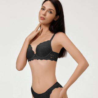Woman wearing a black lace bra and panties set on a light gray background