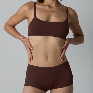 Person wearing a brown sports bra and shorts set on a gray background