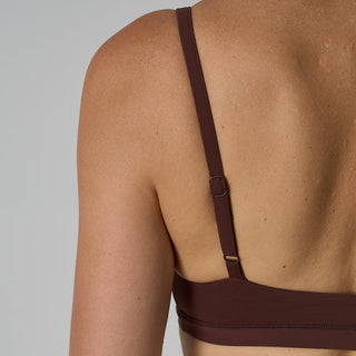 Brown bikini top on a person against a gray background