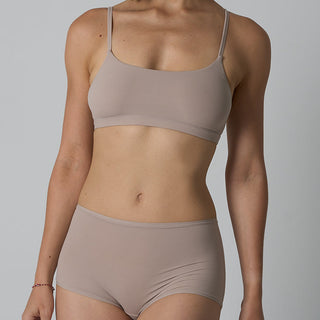 Person wearing a beige bra and underwear set on a plain background