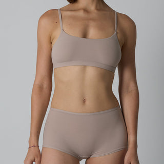 Person wearing a beige bra and underwear set on a plain background