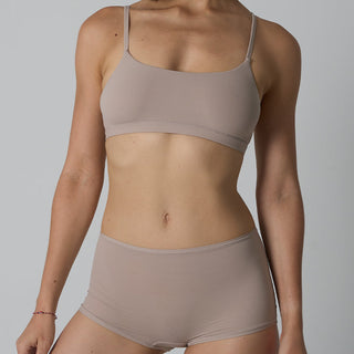 Person wearing a beige bra and underwear set on a plain background