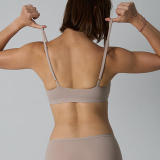 Person wearing a beige bra and underwear set against a plain background