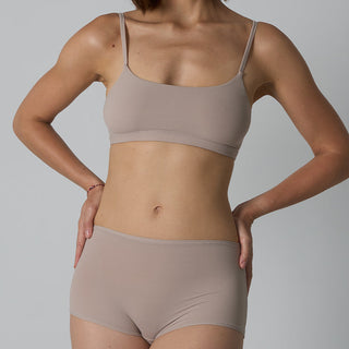Person wearing a beige bra and underwear set against a plain background