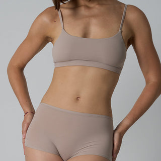 Person wearing a beige bra and underwear set on a plain background