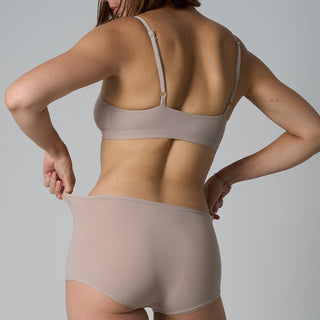Person wearing a beige bra and underwear set against a plain background