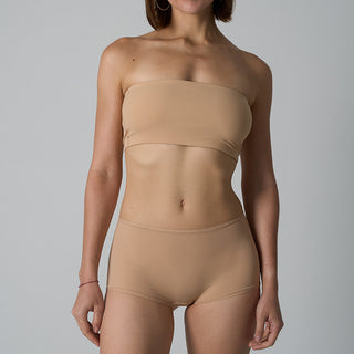 Woman wearing a beige strapless top and high-waisted underwear set on a gray background