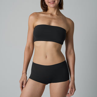 Woman wearing a black strapless top and high-waisted shorts on a gray background