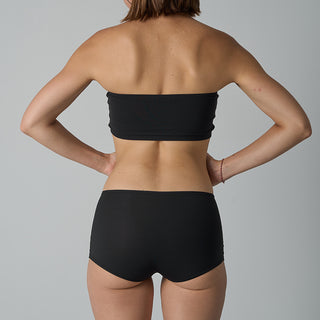 Person wearing a black strapless top and black shorts on a gray background