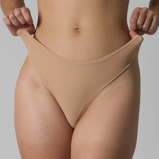 Beige thong being worn against a neutral background