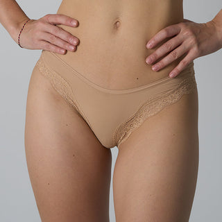 Beige lace-trimmed underwear worn by a person on a gray background