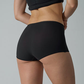 Person wearing black high-waisted shorts on a gray background