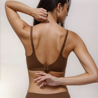 Woman wearing a brown bra and underwear set against a plain background