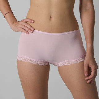 Person wearing light pink underwear with lace trim on a gray background