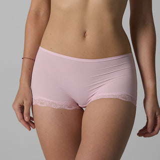 Person wearing light pink underwear with lace trim on a gray background
