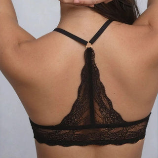 Black lace bra worn by a person on a plain background