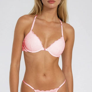 Woman wearing a pink bra and panties set against a plain background