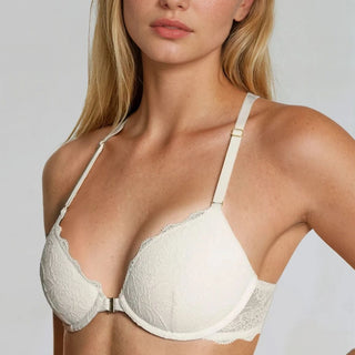 Woman wearing a white lace bra against a plain background