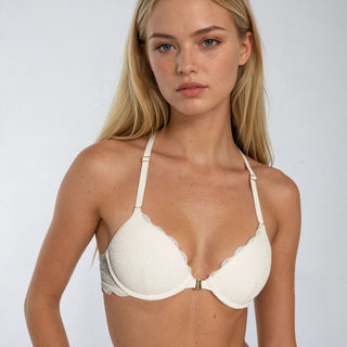 Woman wearing a white bra against a plain background